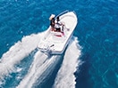 Aerial view of a boat speeding across bright blue water 