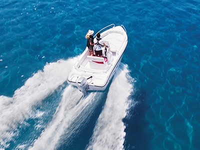 Aerial view of a boat speeding across bright blue water 